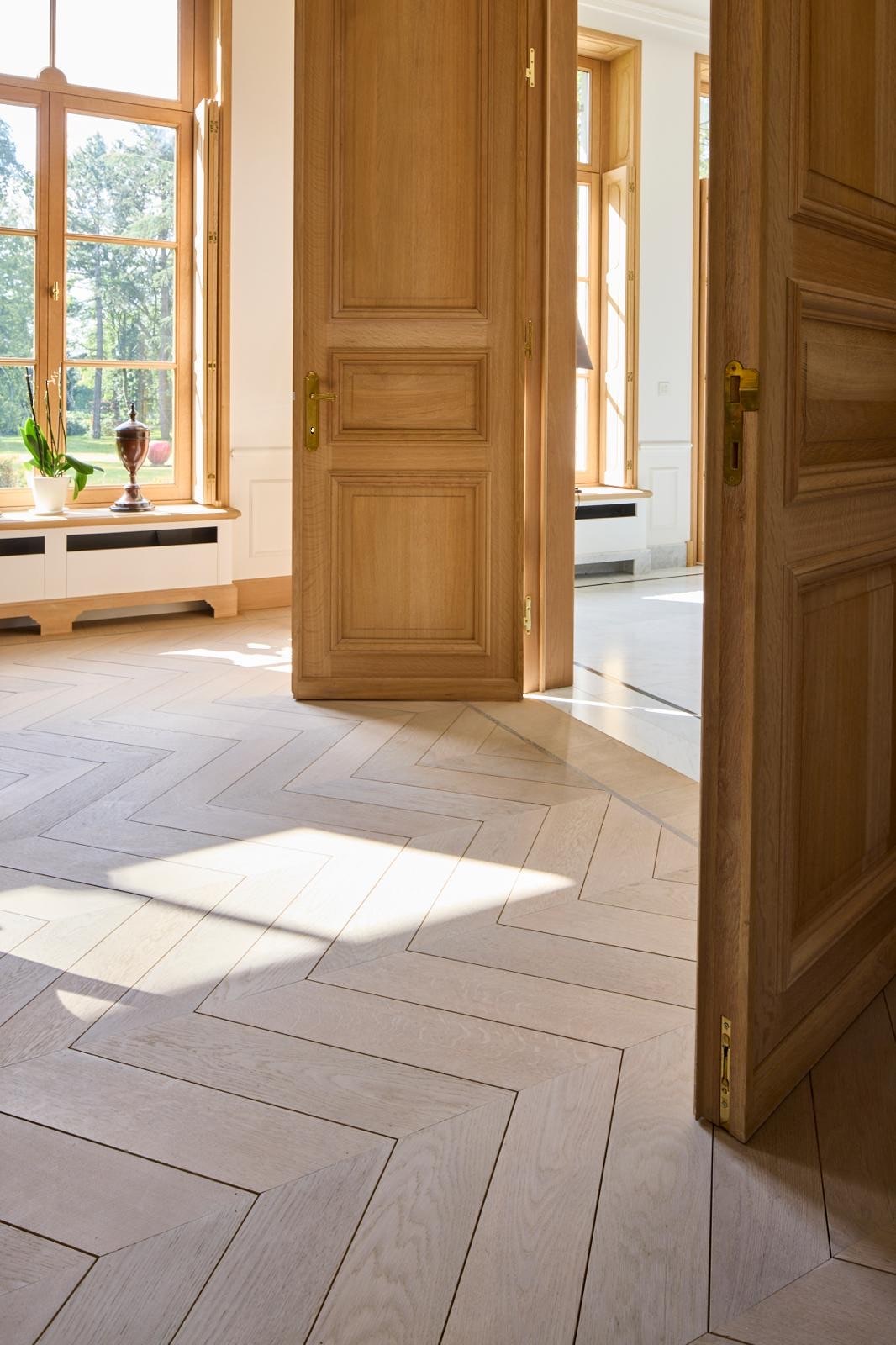 Brede eiken plankenvloer in een lichte leefruimte met walnoten eettafel, gelegd door Grutman Floor Concepts