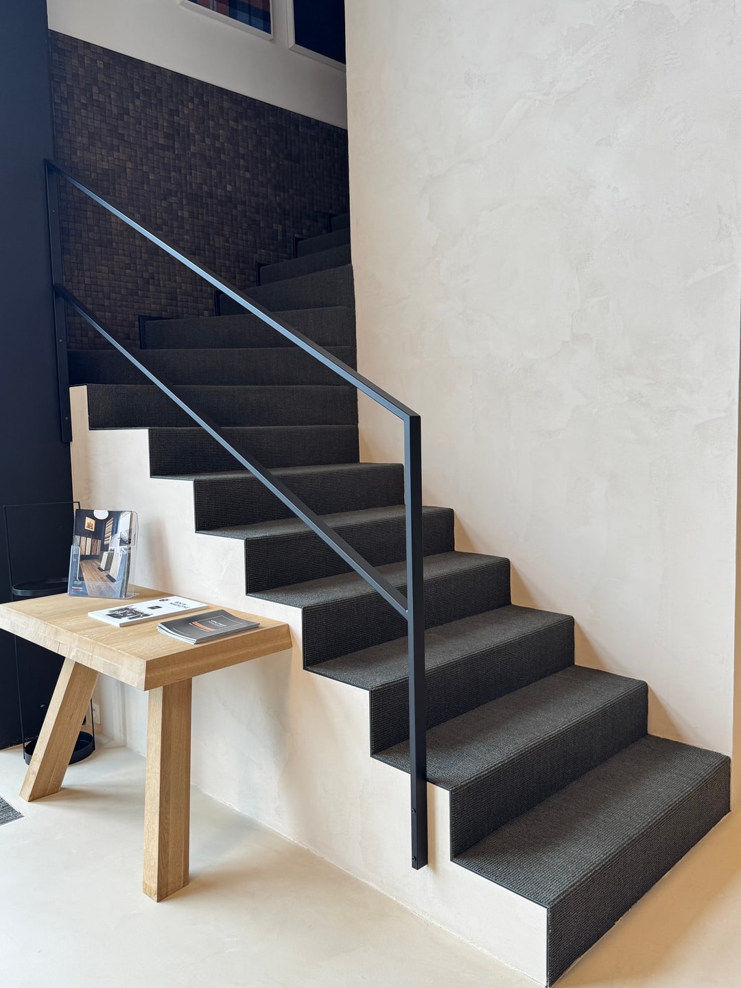 Showroomtrap in antraciet tapijt tegen een naadloze microtopping wand