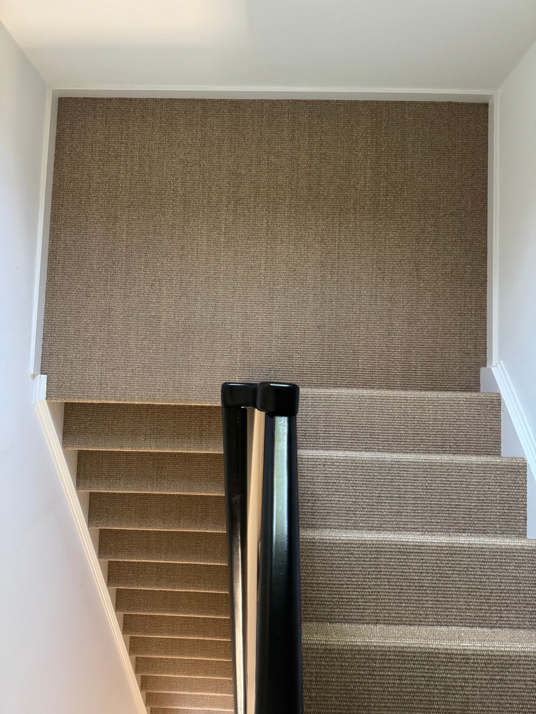 Overloop en trap doorlopend bekleed in naturel sisal-look tapijt met zwarte leuning